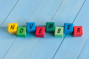 November wooden blocks with many-coloured pumpkins and decor against an old wood background