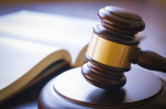 brown gavel and open book on a wooden table of the law in the courtroom