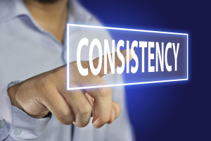 Business concept image of a businessman pointing Consistency icon on virtual screen over blue background
