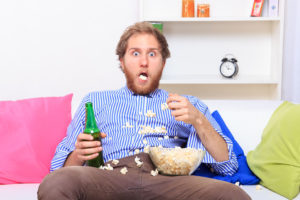 39350638 - surprised man eating popcorn on the sofa at home