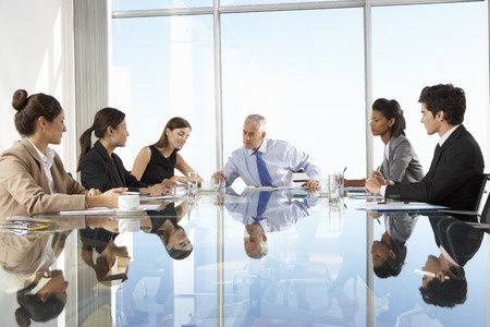 Group of business people having board meeting around glass table