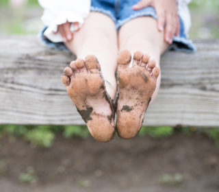 Bare feet of muddy children